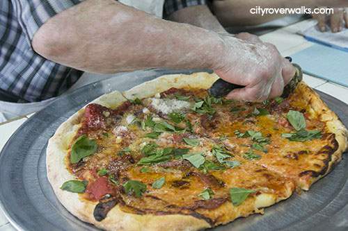 Dom slicing fresh pizza at Di Fara in Brooklyn